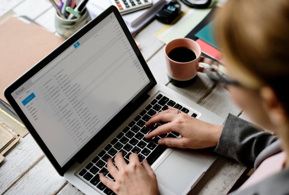 A woman going through her emails on a laptop in a home office. 