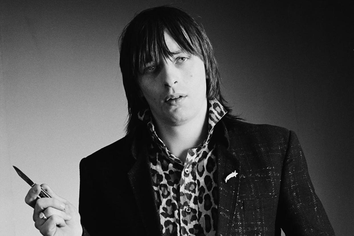 Garry Roberts, guitarist with Irish punk band The Boomtown Rats, wearing a leopard-print shirt and holding a penknife, in a studio portrait, in February 1979. (Photo by Fin Costello/Redferns/Getty Images)