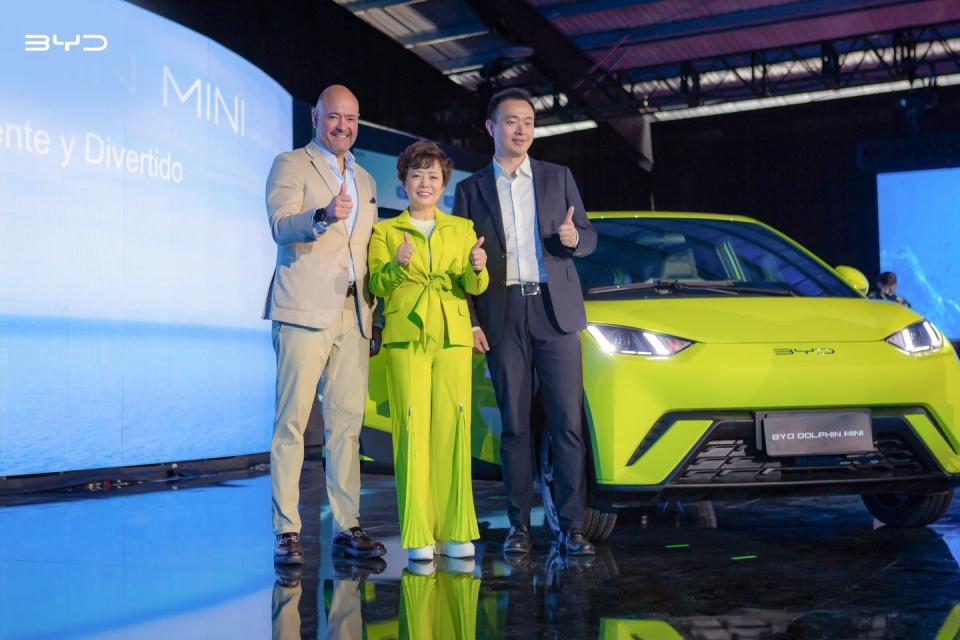 a group of people posing for a photo next to a yellow byd dolphin mini