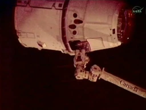 In this frame grab from a NASA video, the robotic arm (bottom) of the International Space Station captures the SpaceX Dragon capsule. The successful maneuver makes SpaceX the first private company to rendezvous with the orbiting lab