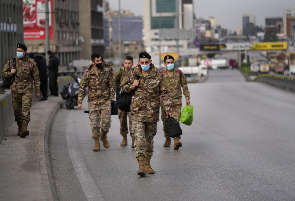 Army soldiers walk on a main highway that blocked by tanker trucks and buses, during a general strike by public transport and labor unions to protest the country's deteriorating economic and financial conditions, in Beirut, Lebanon, Thursday, Jan. 13, 2022. Protesters closed the country's major highways as well as roads inside cities and towns starting 5 a.m. making it difficult for people to move around. (AP Photo/Hussein Malla)
