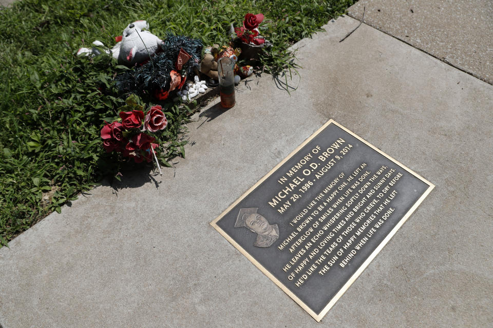 In this July 25, 2019, photo, flowers and other items lay near a memorial plaque in the sidewalk near the spot where Michael Brown was shot and killed by a police officer five years ago in Ferguson, Mo. (AP Photo/Jeff Roberson)