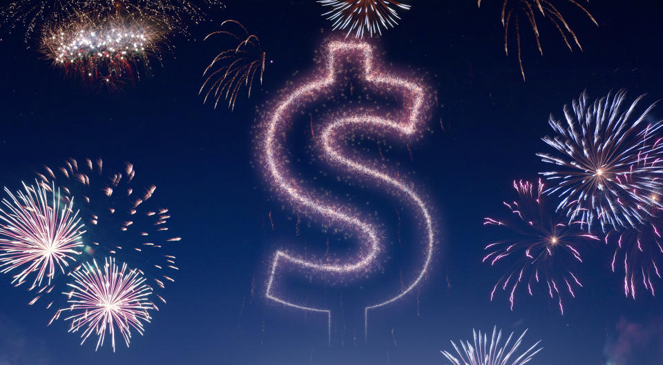 Nighttime fireworks show with a dollar sign in the sky