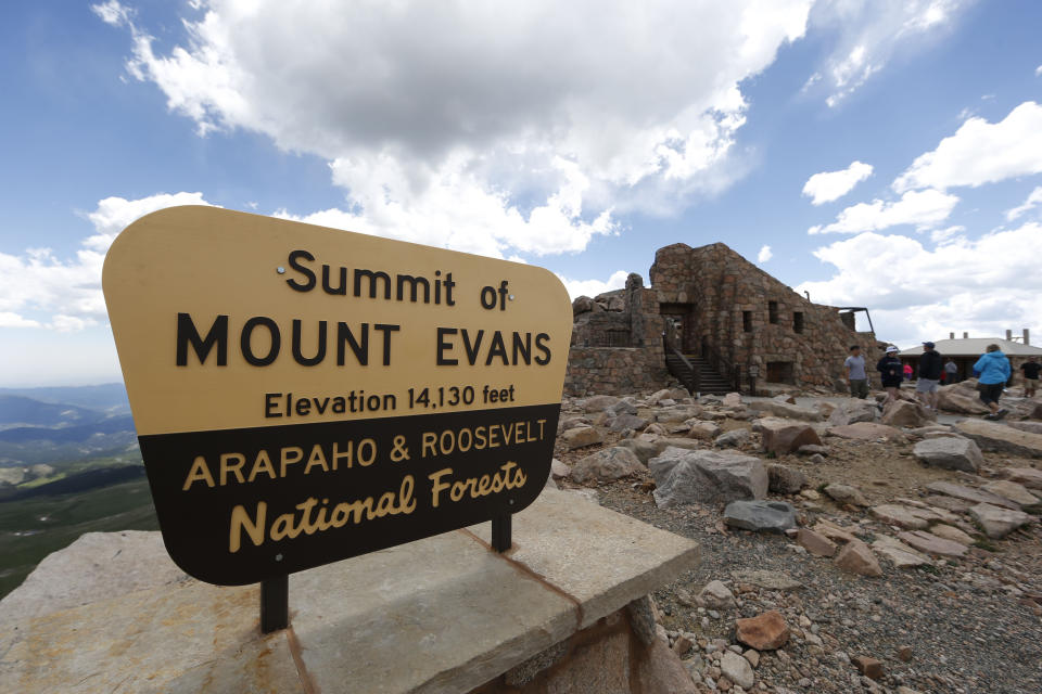 FILE - Visitors pass the sign on the summit of Mount Evans near Idaho Springs, Colo., July 15, 2016. On Friday, Sept. 15, 2023, federal officials renamed the towering mountain southwest of Denver to Mount Blue Sky as part of a national effort to address the history of oppression and violence against Native Americans. (AP Photo/David Zalubowski, File)