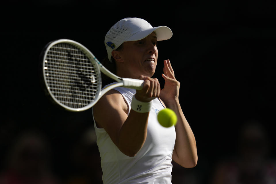 Poland's Iga Swiatek returns to Switzerland's Belinda Bencic in a women's singles match on day seven of the Wimbledon tennis championships in London, Sunday, July 9, 2023. (AP Photo/Kirsty Wigglesworth)