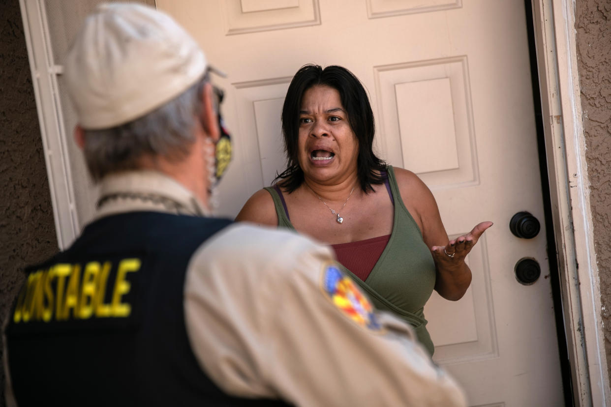 PHOENIX, ARIZONA - OCTOBER 07: A tenant speaks with a Maricopa County constable who arrived with an eviction order on October 7, 2020 in Phoenix, Arizona. The tenant was able to prove she had paid the rent and the order was withdrawn. Thousands of court-ordered evictions continue nationwide despite a Centers for Disease Control (CDC) moratorium for renters impacted by the coronavirus pandemic. Although state and county officials say they have tried to educate the public on the protections, many renters remain unaware and fail to complete the necessary forms to remain in their homes. In many cases landlords have worked out more flexible payment plans with vulnerable tenants, although these temporary solutions have become fraught as the pandemic drags on. With millions of Americans still unemployed due to the pandemic, federal rental assistance proposals remain gridlocked in Congress. The expiry of the CDC moratorium at year's end looms large, as renters and landlord face a potential tsunami of evictions and foreclosures nationwide.  (Photo by John Moore/Getty Images)