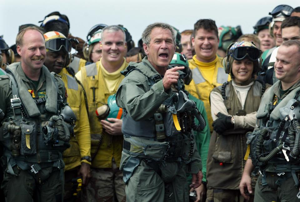 President George W. Bush, wearing a flightsuit after arriving on the flightdeck in an S3?Viking aircraft, shouts out greetings to Navy sailors who work the flightdeck crews as they greeted him with cheers today (5/01/03).