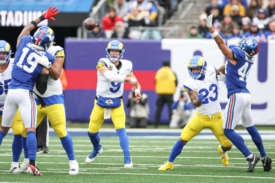 Dec 31, 2023; East Rutherford, New Jersey, USA; Los Angeles Rams quarterback Matthew Stafford (9) throws the ball as New York Giants safety Isaiah Simmons (19) and cornerback Nick McCloud (44) defend during the first half at MetLife Stadium. Mandatory Credit: Vincent Carchietta-USA TODAY Sports