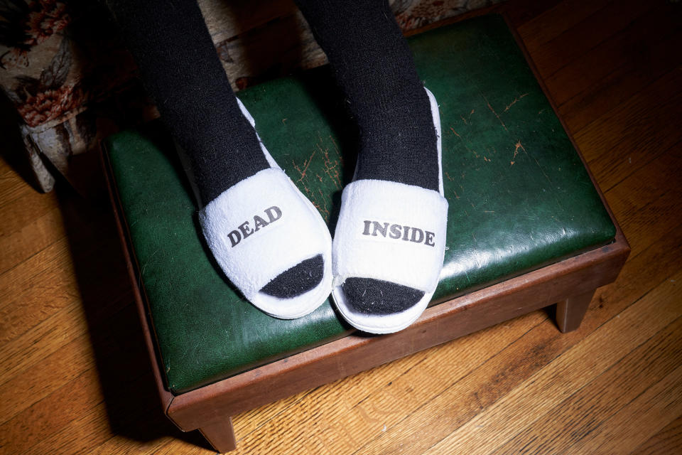socked feet in slippers that say "dead" and "inside" 