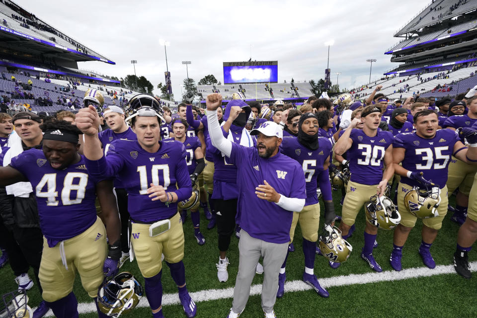 Washington head coach Jimmy Lake, center, leads the team in singing the school fight song to fans after the team beat Arkansas State in an NCAA college football game Saturday, Sept. 18, 2021, in Seattle. Washington won 52-3. (AP Photo/Elaine Thompson)