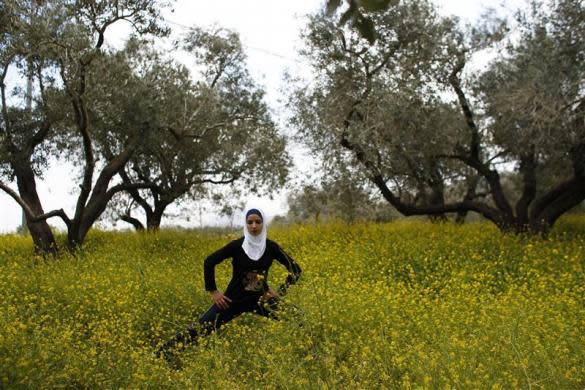 Palestinian runner Worood Maslaha, 20, stretches as she practices with her trainer Saher Jura (unseen) at a field belonging to her family in the West Bank village of Asira Ash-Shamaliya near Nablus, March 27, 2012.