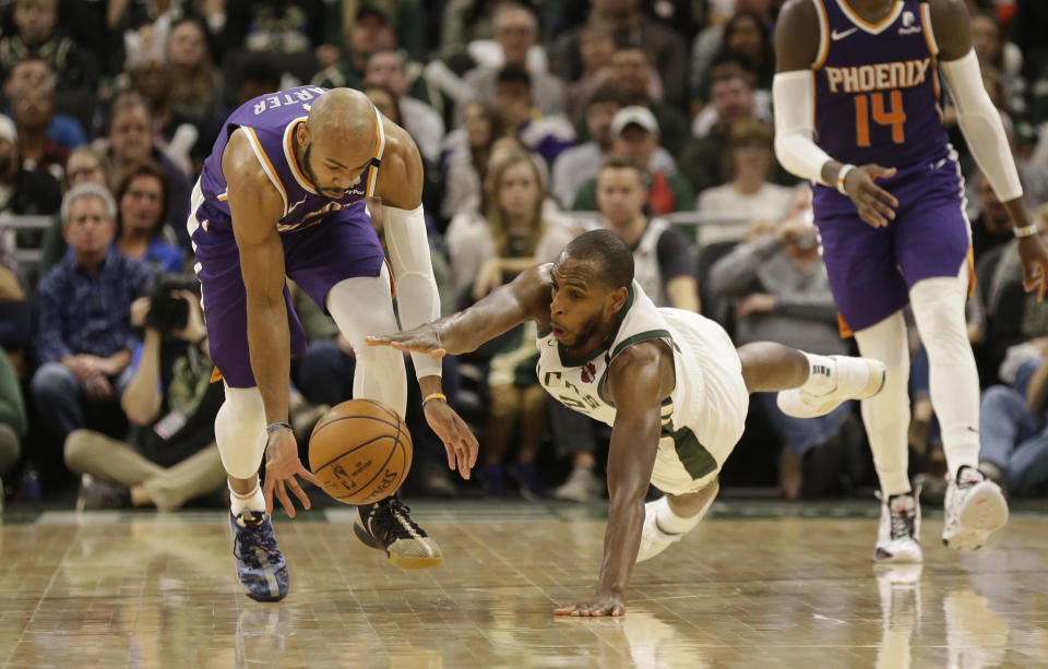 Phoenix Suns' Jevon Carter, left, reaches for the ball against Milwaukee Bucks' Khris Middleton, center, during the second half of an NBA basketball game Sunday, Feb. 2, 2020, in Milwaukee. (AP Photo/Jeffrey Phelps)