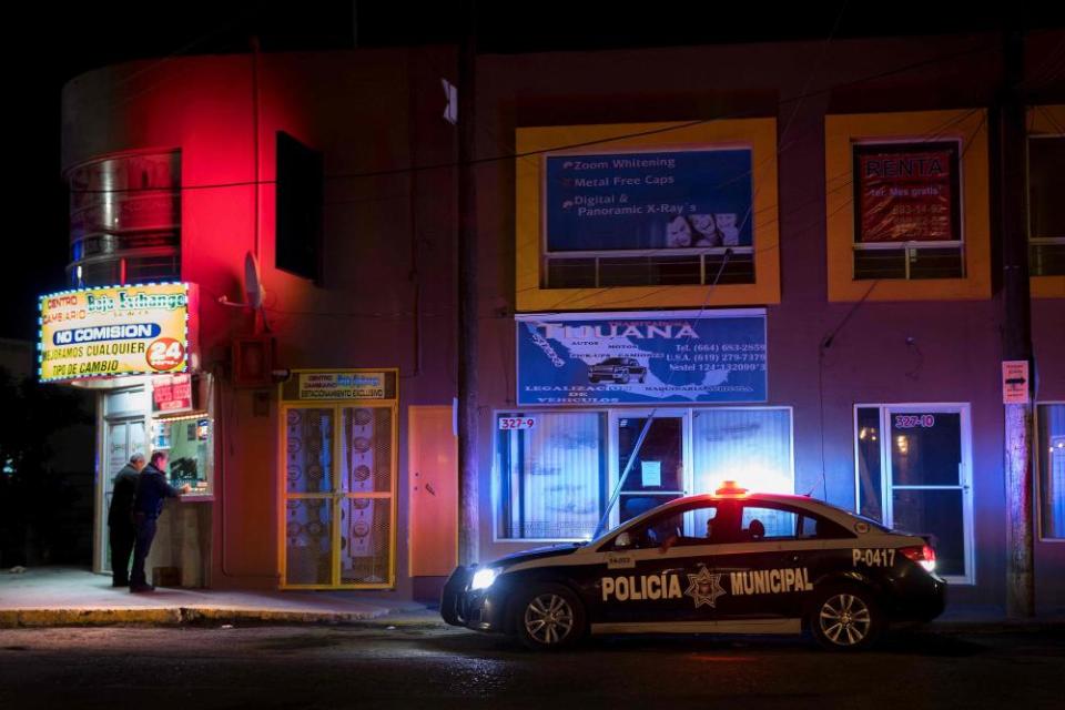 Municipal police patrol the area by a money exchange near the border in Tijuana, Mexico