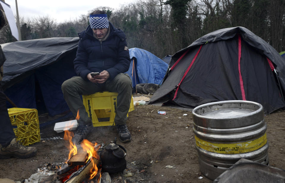 In this photo taken Tuesday, Jan.15, 2019. Ahmed, from Ahwaz in southwest Iran, checks his phone in Calais, northern France. Border control officers patrolling the land, sea and air of northern France are combing beaches, dunes and the frigid, murky coastal waters in a bid to end a high-risk but growing tactic by a group of mostly Iranian migrants desperate to get to Britain: sneaking across the English Channel in rubber boats. (AP Photo/Michel Spingler)