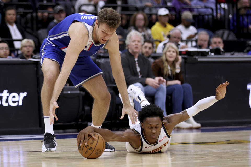 Sacramento Kings forward Sasha Vezenkov, left, and Denver Nuggets forward Peyton Watson reach for the ball during the second half of an NBA basketball game in Sacramento, Calif, Saturday, Dec. 2, 2023. (AP Photo/Jed Jacobsohn)