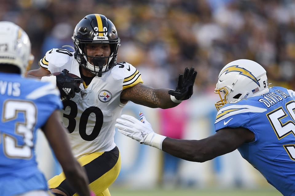 Pittsburgh Steelers running back James Conner, left, holds by Los Angeles Chargers outside linebacker Thomas Davis as he runs the ball during the first half of an NFL football game, Sunday, Oct. 13, 2019, in Carson, Calif. (AP Photo/Kelvin Kuo)