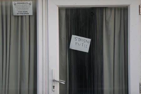 A sign that reads "Staying Put" is seen in the window of a home the village of Jaywick which is threatened by a storm surge, in Essex, Britain January 13, 2017. REUTERS/Stefan Wermuth