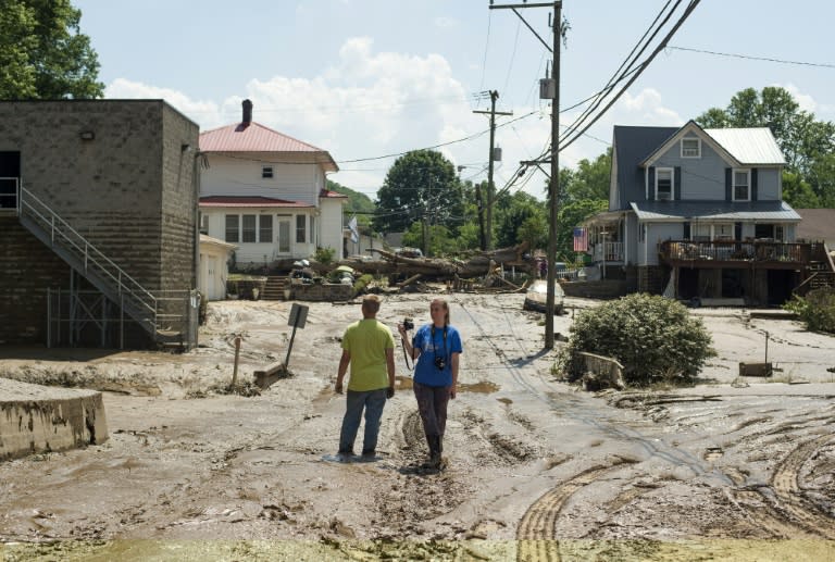 People stand in the middle of a mud covered street left over from the flooding of the Elk River in Clendenin, West Virginia