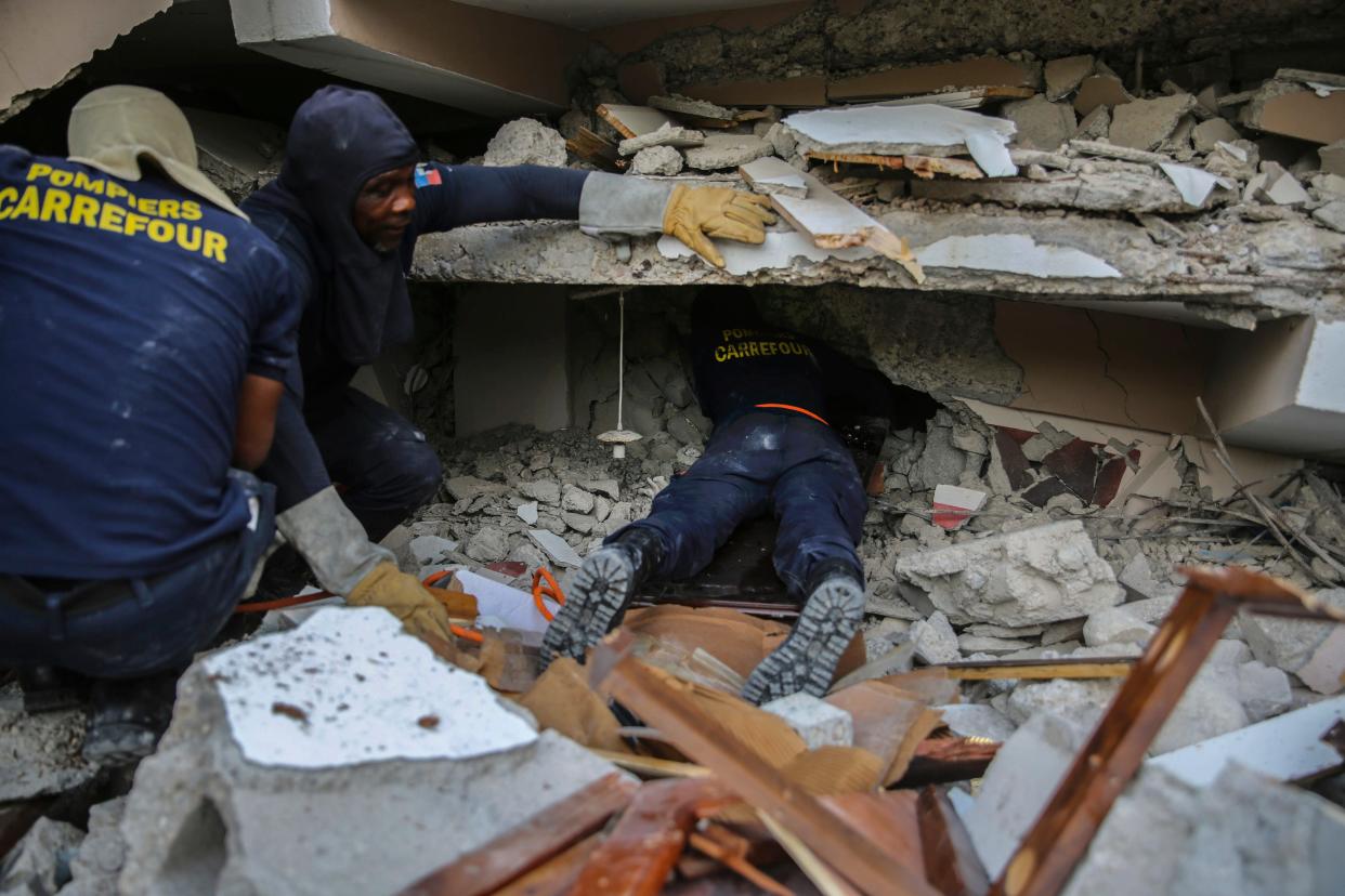 Firefighters search for survivors inside a collapsed building in the Haitian city of Les Cayes  (AP)