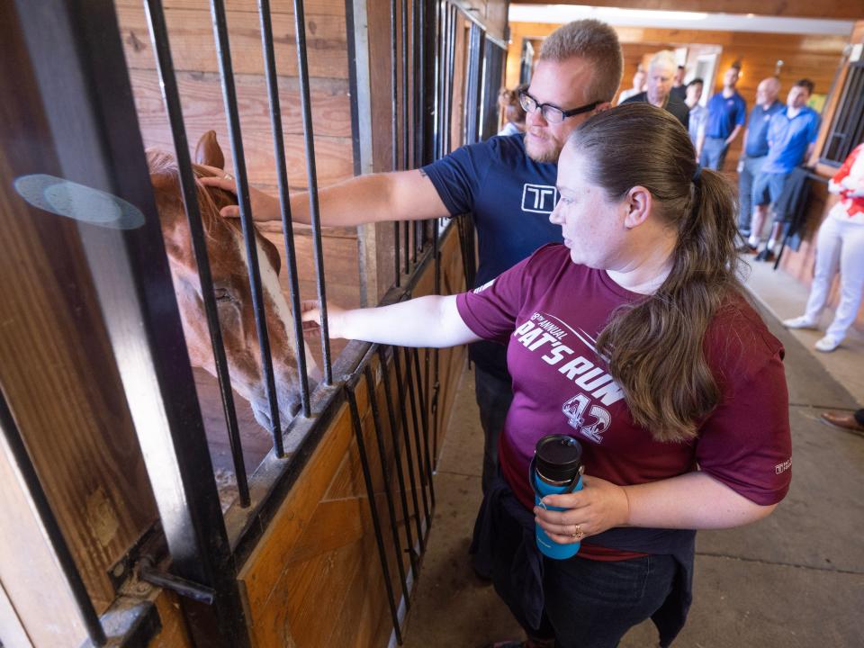 Pat Tillman Foundation scholars Gretchen Klingler and David Hibler pet a horse during a tour of the stables at Pegasus Farm-run Military and First Responders Center in Nimishillen Township.