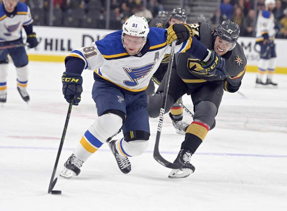 St. Louis Blues right wing Vladimir Tarasenko (91) and Vegas Golden Knights defenseman Shea Theodore (27) vie for the puck during the first period of an NHL hockey game Wednesday, Oct. 20, 2021, in Las Vegas. (AP Photo/David Becker)