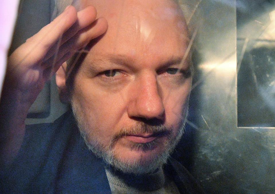 WikiLeaks founder Julian Assange gestures from the window of a prison van as he is driven out of Southwark Crown Court in London on May 1, 2019, after having been sentenced to 50 weeks in prison for breaching his bail conditions in 2012.