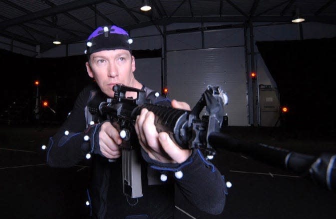 Steen Young in a motion capture suit holding a gun.
