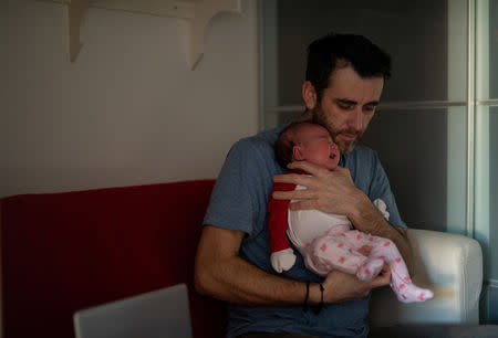 Adi, 37, who works for a removal company, holds his baby daughter, Ioana who is a few weeks old, at their home in London, Britain, February 22, 2019. REUTERS/Alecsandra Dragoi