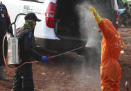 A worker sprays a colleague with disinfectant after a burial of someone who presumably died of COVID-19 at a cemetery in Jakarta, Indonesia Friday, June 12, 2020. As Indonesia’s virus death toll rises, the world’s most populous Muslim country finds itself at odds with protocols put in place by the government to handle the bodies of victims of the pandemic. This has led to increasing incidents of bodies being taken from hospitals, rejection of COVID-19 health and safety procedures, and what some experts say is a lack of communication from the government. (AP Photo/Achmad Ibrahim)