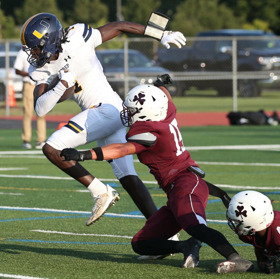 University Prep wide receiver Tyrell Simmons sheds the tackle attempts by Aquinas's Jeffery Logan III and Noah Collins Howard to score on a long pass play in the first half during UPrep's season opener at Aquinas. UPrep won the game 33-7.