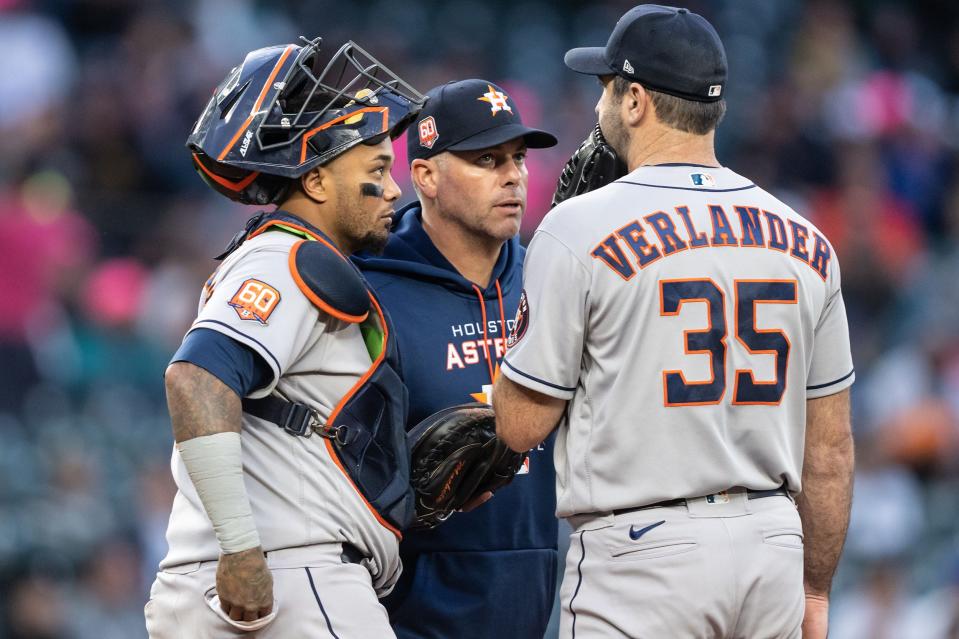 Catcher Martin Maldonado, pitching coach Joshua Miller and starting pitcher Justin Verlander of the Houston Astros meet at the mound during a game against the Seattle Mariners on May 27, 2022 in Seattle, Washington.