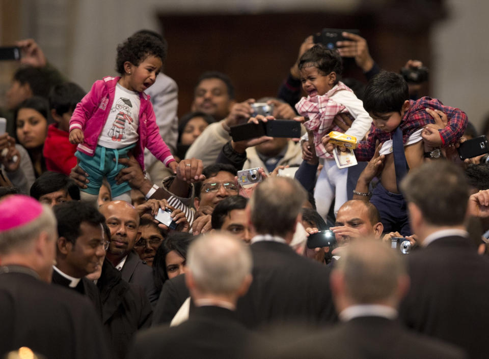 Children cry as they are lifted while Pope Francis, partially hidden by security at center, arrives in St. Peter's Basilica at the end of a mass for the Sri Lankan community, at the Vatican, Saturday, Feb. 8, 2014. (AP Photo/Alessandra Tarantino)