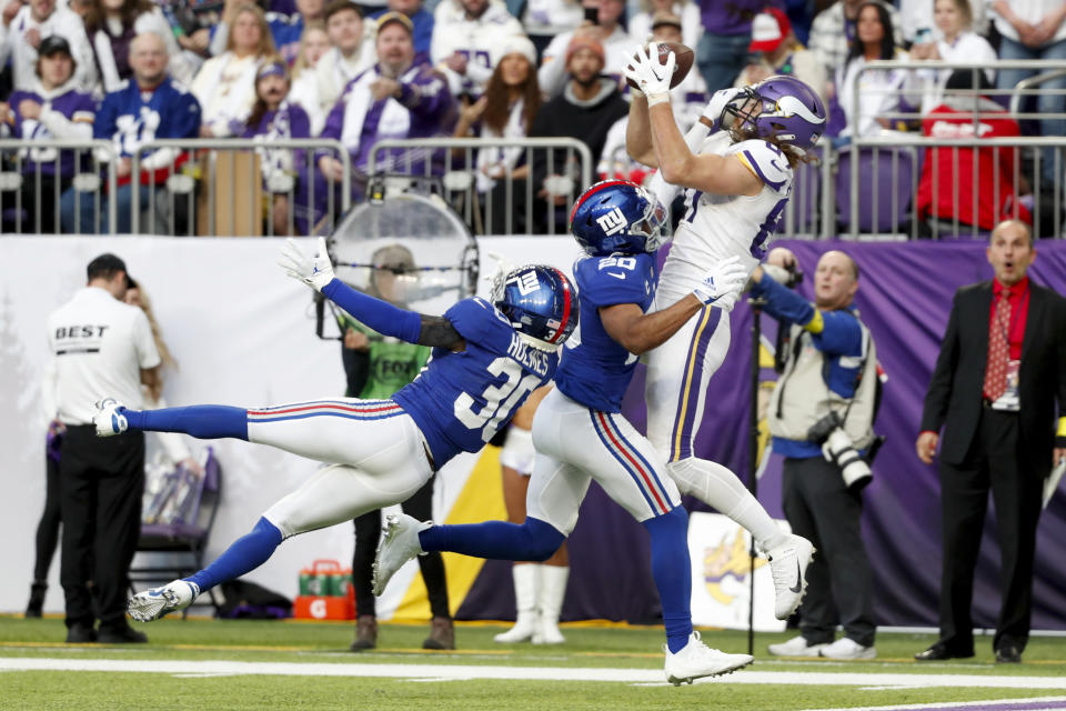 Minnesota Vikings tight end T.J. Hockenson, right, catches a 15-yard touchdown pass over New York Giants safety Julian Love (20) and cornerback Darnay Holmes (30) during the second half of an NFL football game, Saturday, Dec. 24, 2022, in Minneapolis. (AP Photo/Bruce Kluckhohn)