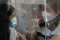 A health worker shows an empty syringe after inoculating a woman with AstraZeneca's COVID-19 vaccine during the first day of a nationwide three-day vaccination drive at a school in Quezon city, Philippines on Monday, Nov. 29, 2021. There has been no reported infection so far caused by the new variant in the Philippines, a Southeast Asian pandemic hotspot where COVID-19 cases have considerably dropped to below 1,000 each day in recent days, but the emergence of the Omicron variant has set off a new alarm. (AP Photo/Aaron Favila)