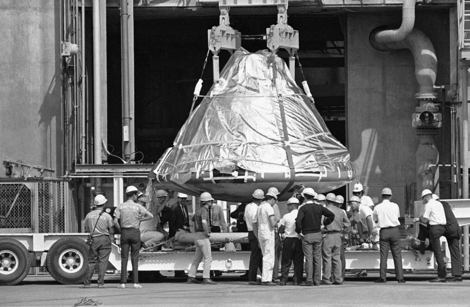 FILE - In this Feb. 17, 1967 file photo, technicians and officials inspect the aluminum covered Apollo 1 spacecraft after it was lowered from its booster at pad 34 at Cape Kennedy, Fla. Astronauts Virgil Grissom, Edward White and Roger Chaffee lost their lives when a flash fire erupted in the spacecraft on January 27. (AP Photo/Jim Kerlin, Pool)