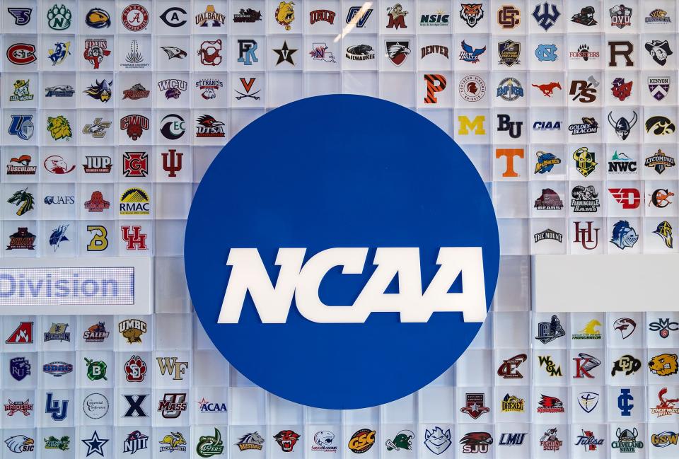 University logos cover a wall in the lobby of NCAA headquarters Thursday, Feb. 25, 2021, in Indianapolis. 