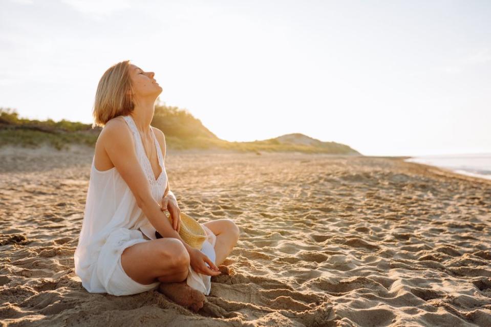 mujer sentada en la playa relajada