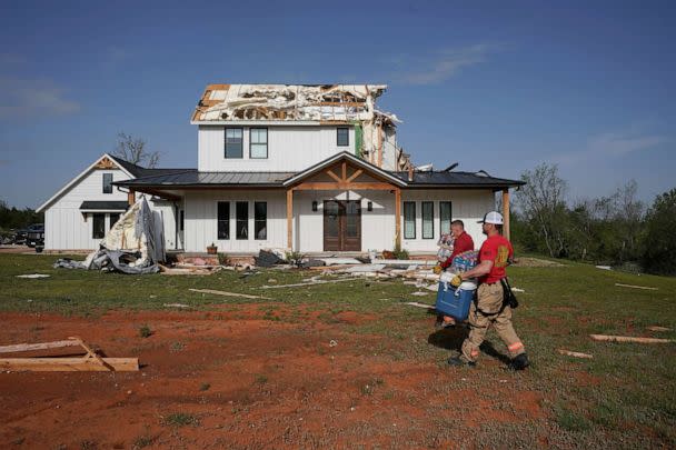 PHOTO: People walk past the damaged house destroyed during overnight tornadoes in Cole, Okla., April 20, 2023. (Nick Oxford/Reuters)