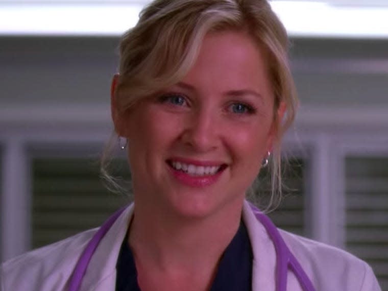 Jessica Capshaw as Arizona on Greys Anatomy wearing a white coat and smiling