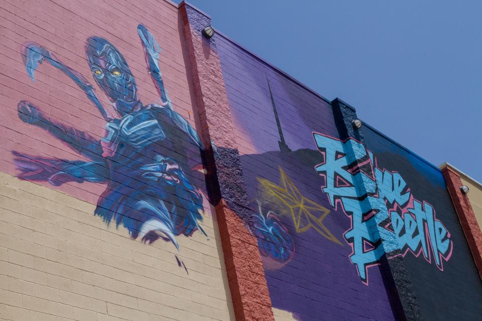 A new mural of the new Blue Beetle movie is being created on the Cinemark 20 movie theatre in El Paso, Texas. The mural is being painted by Jesus "Cimi" Alverado in collaboration with Warner Brothers.