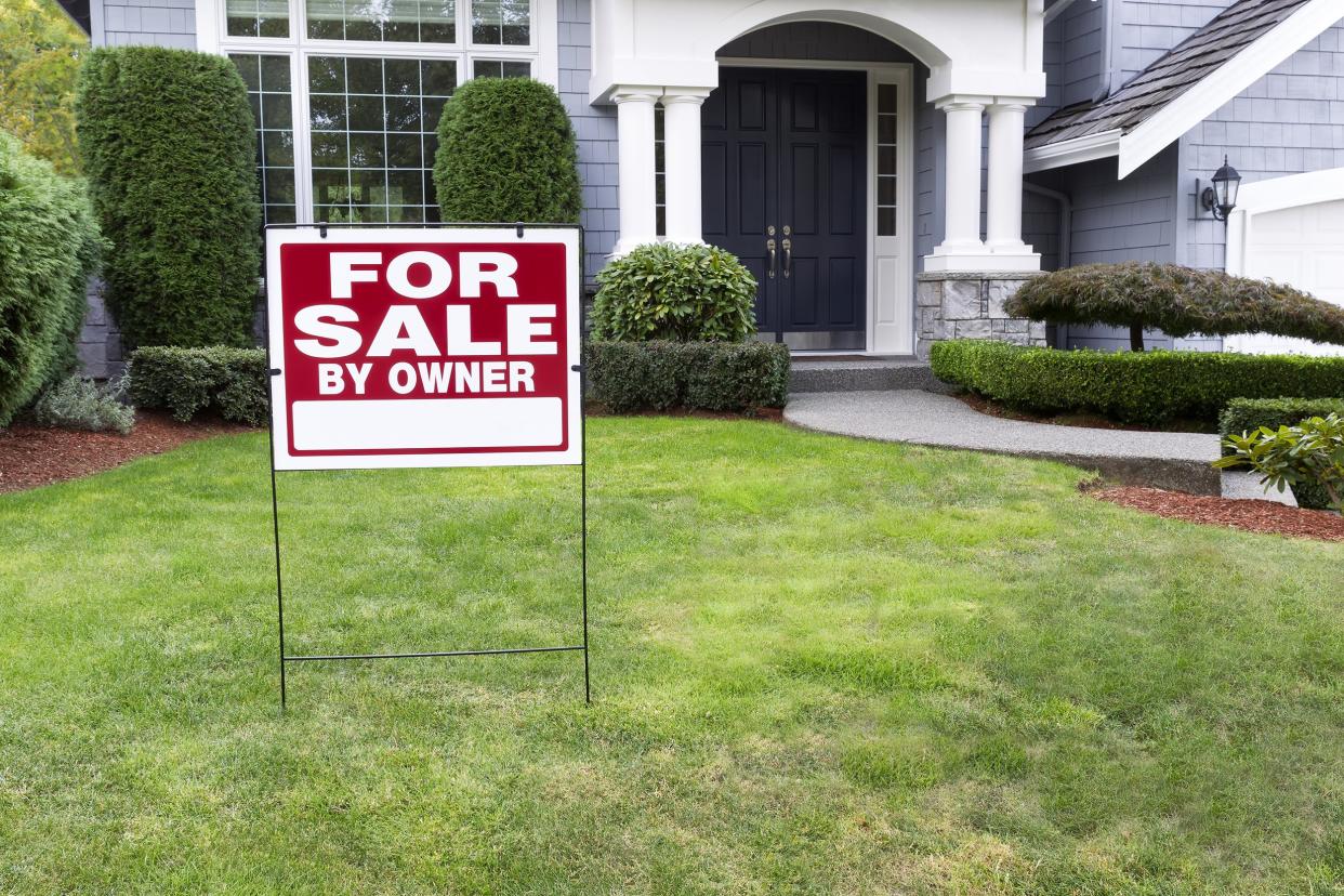 House with a 'For Sale by Owner' sign in the front yard