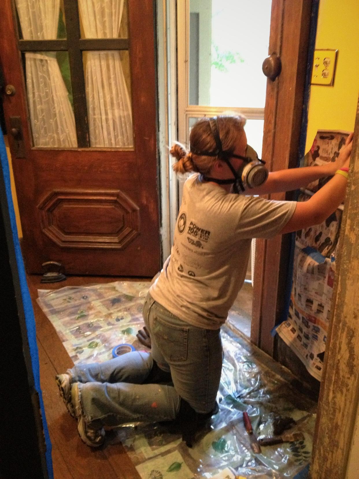 In 2013, daughter No. 2 picks up where daughter No. 3 left off as they tag-teamed the process of stripping paint from woodwork in the front hallway of our old house. The front door, with its crude, four-pane replacement for the original window glass, is visible in the background.