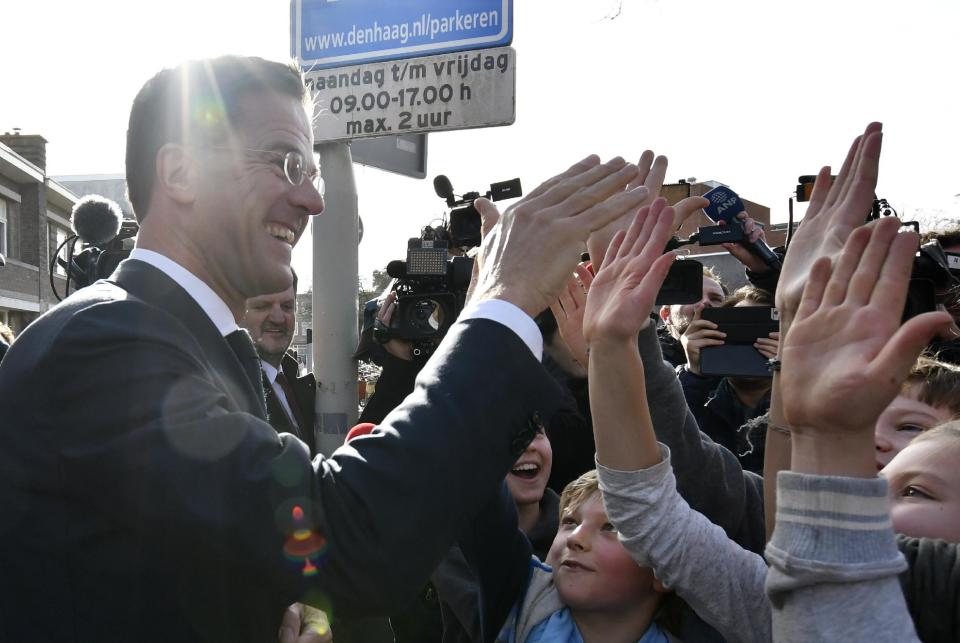 Dutch Prime Minister Mark Rutte gives 'high five' to children after casting his vote for the Dutch general election in The Hague, Netherlands, Wednesday, March 15, 2017. (AP Photo/Patrick Post)