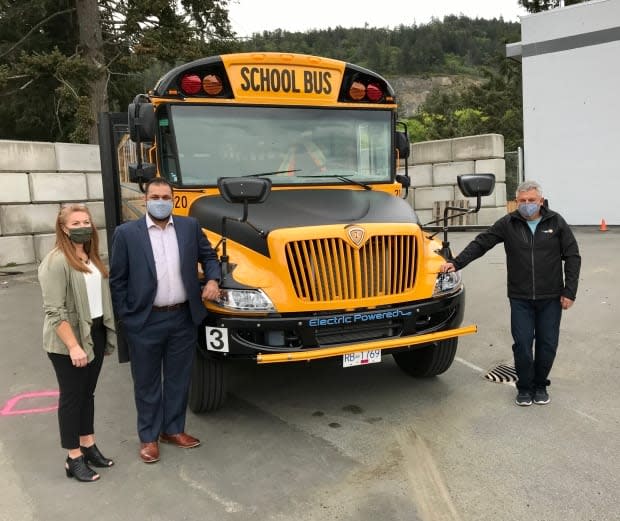 Tracey Syrota, Ravi Parmar and bus driver Al Kowalko stand with one of the Sooke school district's new electric school buses.  (School District 62/Twitter - image credit)