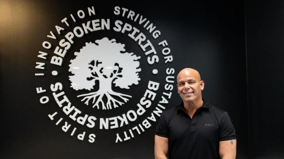 Bespoken Spirits CEO Peter Iglesias poses in front of a wall sign within the distillery’s tasting room In Greyline Station on West Loudon Avenue.