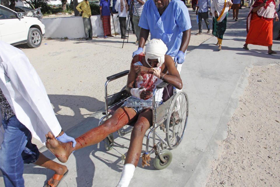A civilian who was wounded in suicide car bomb attack is helped at check point in Mogadishu, Somalia, Saturday, Dec, 28, 2019. A police officer says a car bomb has detonated at a security checkpoint during the morning rush hour in Somalia's capital. (AP Photo/Farah Abdi Warsame)
