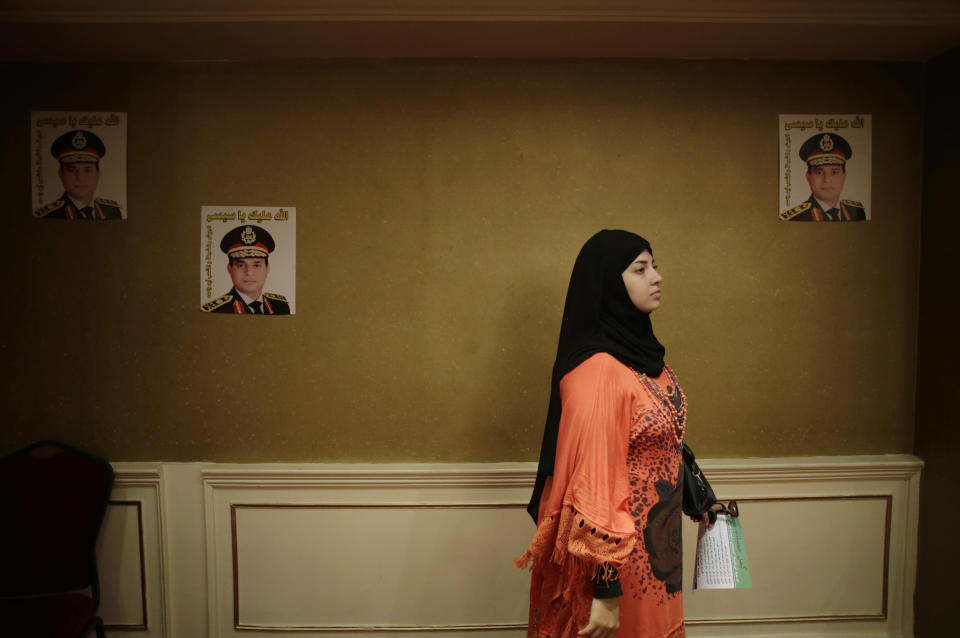 FILE - In this Monday, Sept. 16, 2013 file photo, an Egyptian woman holds a petition form to nominate Defense Minister Gen. Abdel-Fattah el-Sissi to run for president while listening to a talk in a campaign at a hotel in Cairo, Egypt. Posters of Defense Minister el-Sissi are taped on the wall. The Arabic on the posters reads, "God bless you, Sissi," and "Army, police and all Egyptians, One arm." Having secured victory in a referendum on a relatively liberal constitution that he championed, insiders say Egypt's military chief is turning his attention to the country’s overwhelming array of problems _ from health and education to government subsidies and investment. The revelations offer the latest indication that Gen. Abdel-Fattah el-Sissi is planning a run for president, capping a stunning transformation for the 59-year-old who started in the infantry. (AP Photo/Hiro Komae, File)