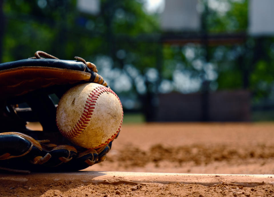 Baseball in glove laying on pitcher's mound of ball field. 