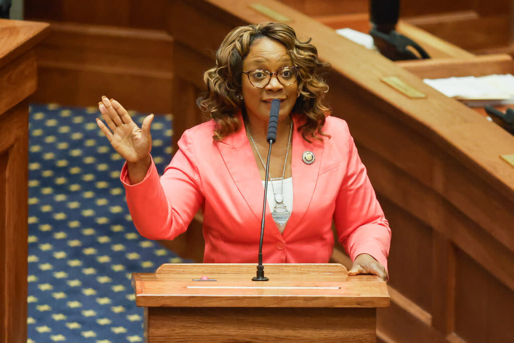 A woman speaking at a podium and gesturing.