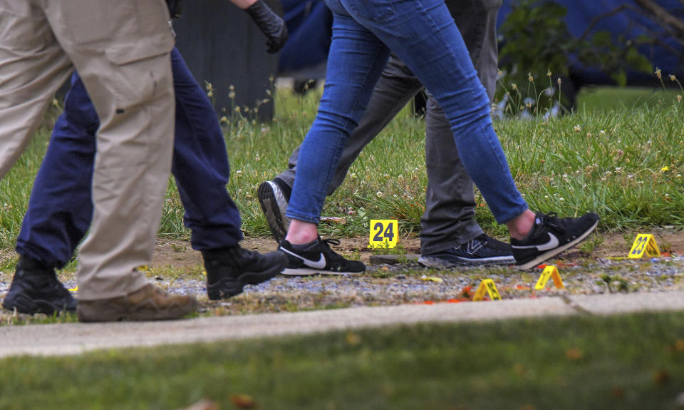 Annapolis Police and other authorities walk among the many evidence markers, Monday, June 12, 2023, as they move to the home belonging to the person suspected of shooting and killing three people and wounding three others in Annapolis, Md., on Sunday evening. (Karl Merton Ferron/The Baltimore Sun via AP)